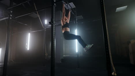 workout-in-sport-club-young-slender-woman-is-hanging-on-crossbar-and-lifting-legs-up